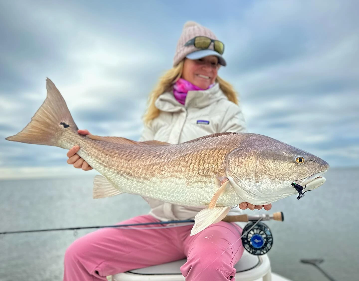 Meredith McCord holding a large fish while fly fishing in shallow water