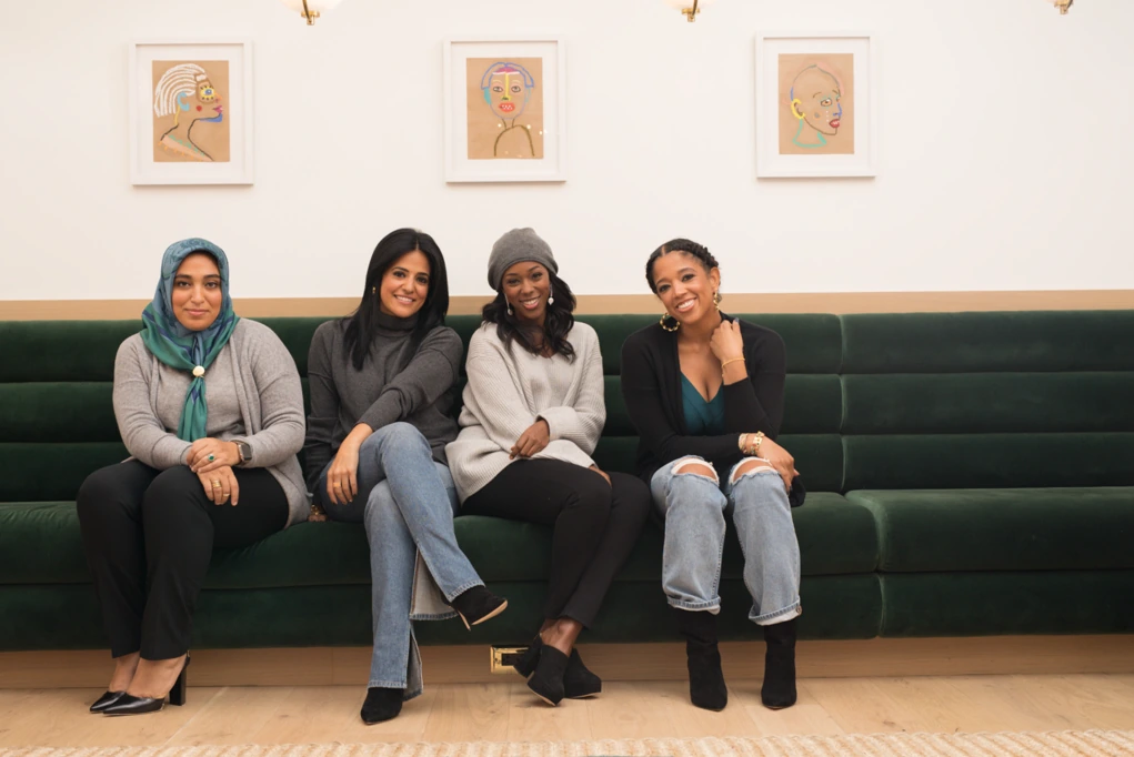 Meredith Koop seated with three other women on a green velvet couch in a bright room