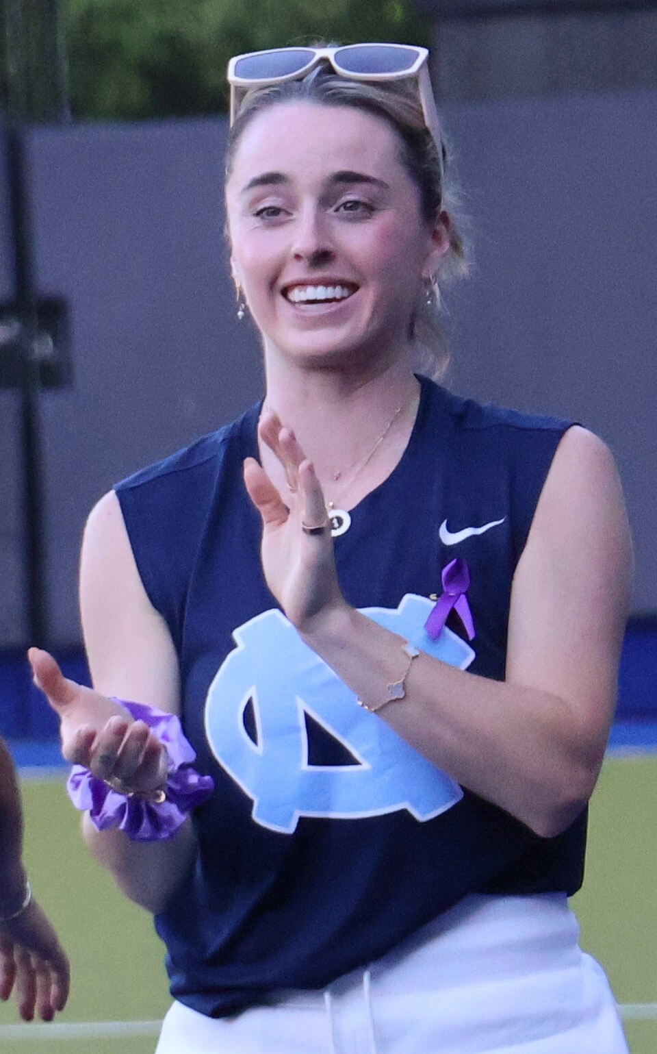 Erin Matson smiling on the field in a North Carolina UNC sleeveless top with sunglasses on her head