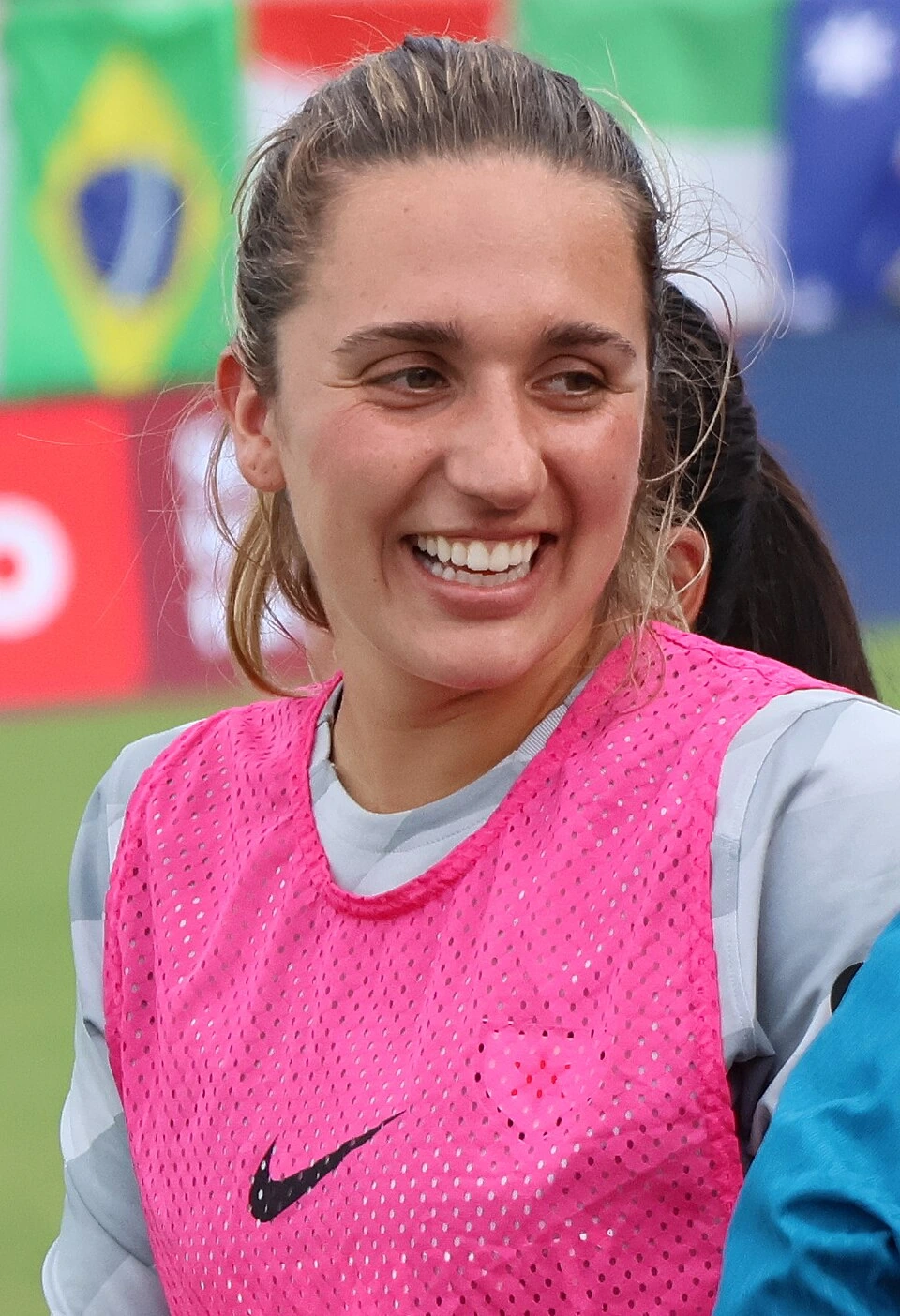 Portrait of Australian soccer goalkeeper Mackenzie Arnold in training gear, smiling on the field.