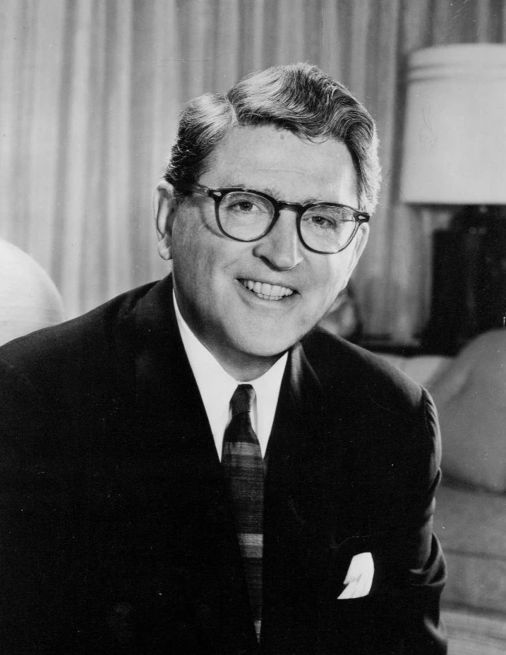 Black-and-white portrait of Meredith Willson wearing glasses and a suit.
